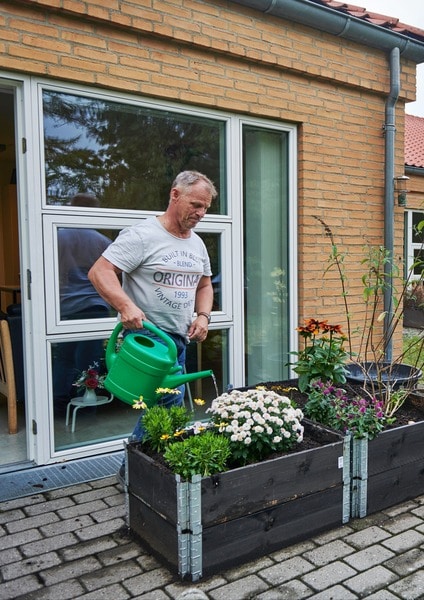 Beboer vander blomster på terrassen, som hører med til boligen på døgn-og dagtilbuddet Brommeparken, Filadelfia