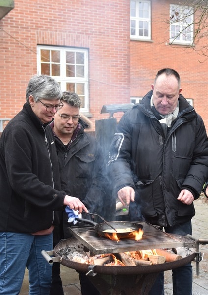 Foto af brugere og medarbejder på Rehabilitering og Udviklingscenter, Filadelfia, som bager pandekager over bål