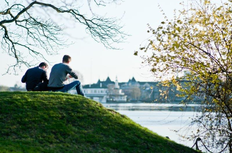 To unge mænd sidder på græsset og snakker